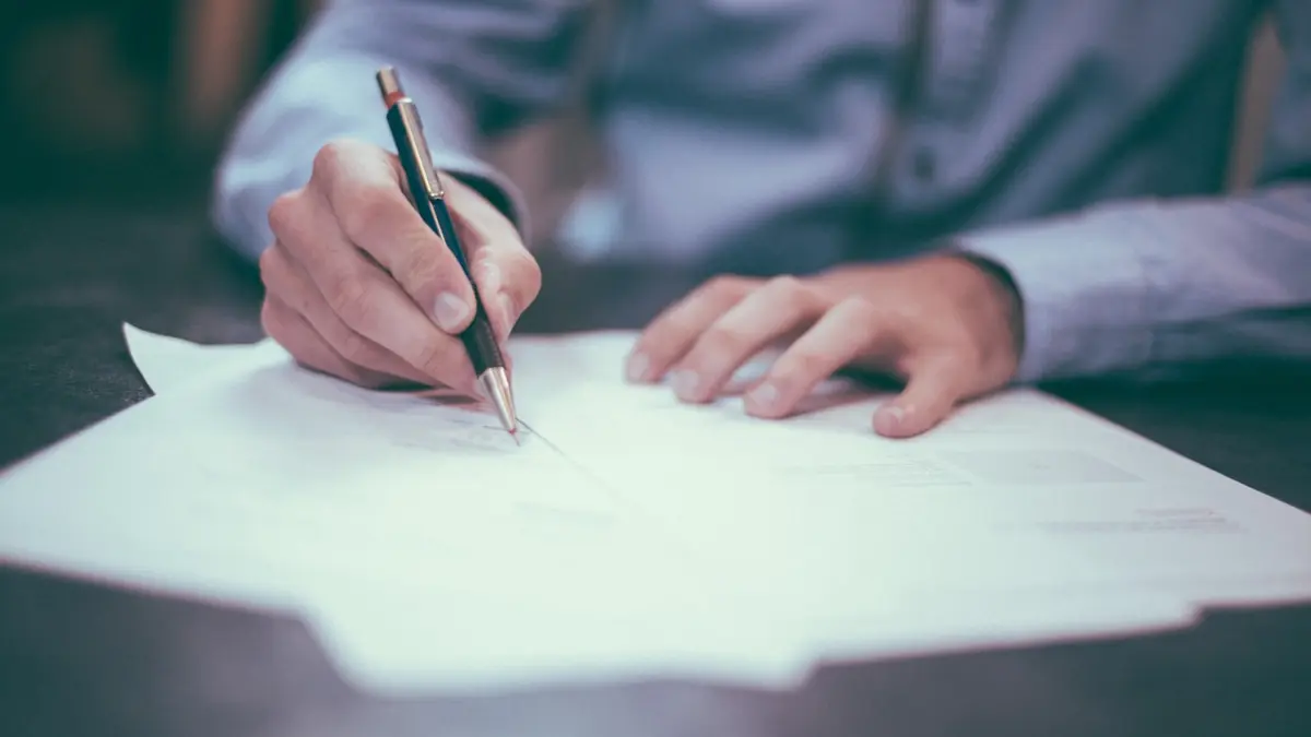 Hand unterschreibt eine Papierrechnung mit Stift – bei Kleinunternehmern noch Alltag